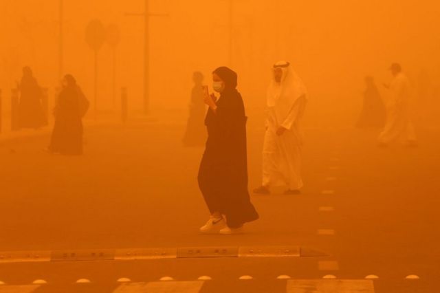 كويتيون يسيرون في الشارع وسط عاصفة ترابية قوية تضرب الكويت