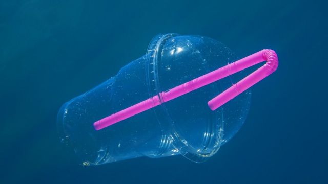 Plastic cup with straw floating in the ocean