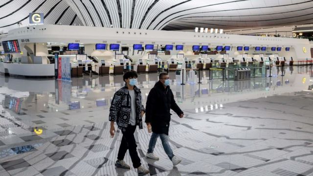 Two men walk by a very empty Daxing international airport in Beijing