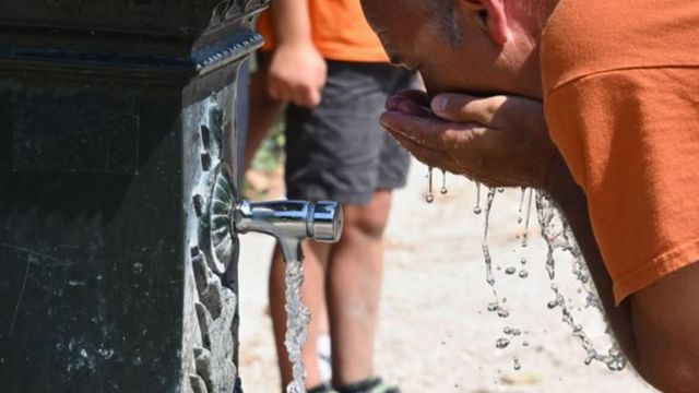 Homem bebendo água em bebedouro