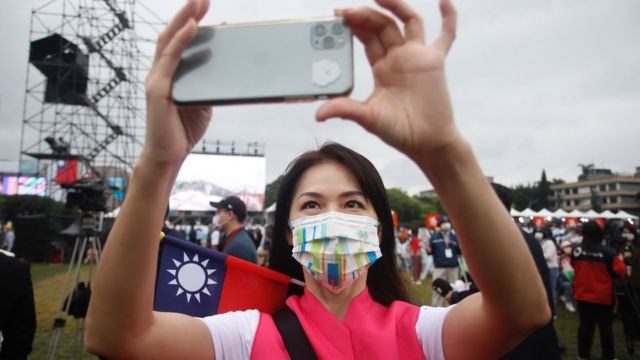 A participant with a Taiwanese flag takes pictures using an iPhone during Taiwan