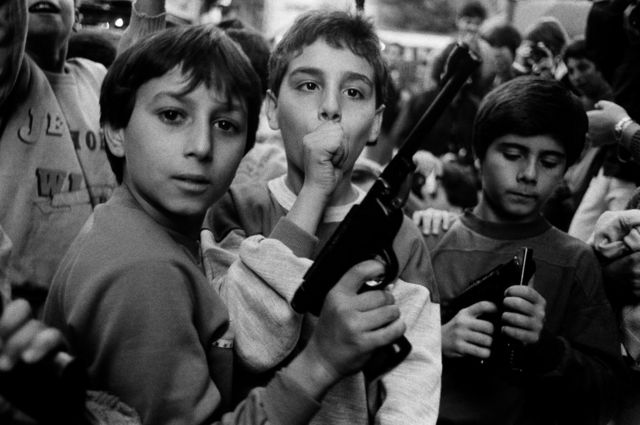 مجموعة من الأطفال يلوحون بمسدسات للمصور.