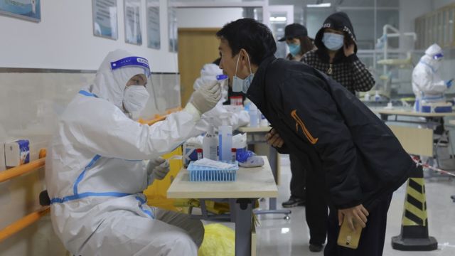 Profissional de saúde paramentado coleta amostra de paciente na China