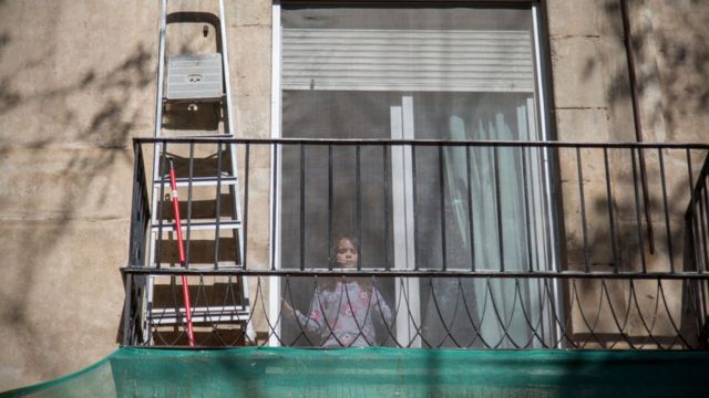 A girl in confinement looks out the window in Barcelona in April