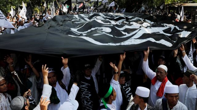 Massa membawa bendera Tauhid saat unjuk rasa di depan kantor Kementerian Politik Hukum dan Keamanan di Jakarta.