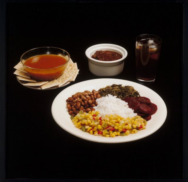 A meal featuring, beans, rice, sweetcorn, crackers and cola
