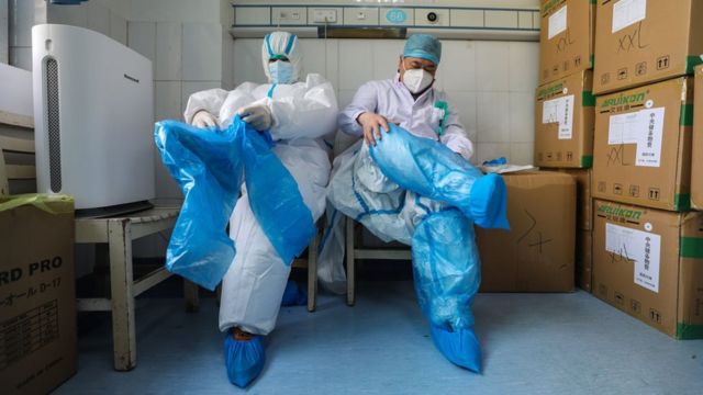 Dois profissionais de saúde vestem equipamentos de proteção em um hospital de Wuhan, na China