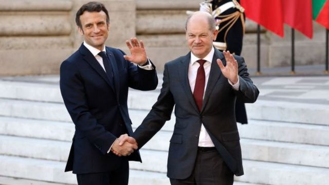 France's President Emmanuel Macron greets Germany's Chancellor Olaf Scholz (R) at the Palace of Versailles, near Paris, on March 10, 2022