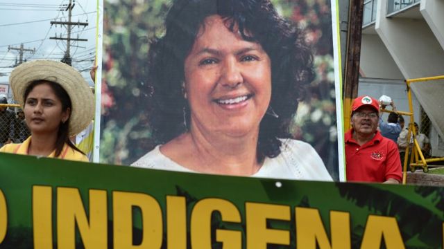 Dos personas llevan una pancarta con la foto de Berta Cáceres