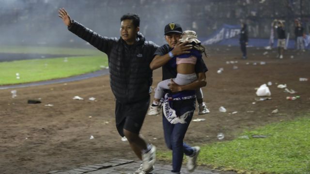 Hombre carga a un bebe en el partido.