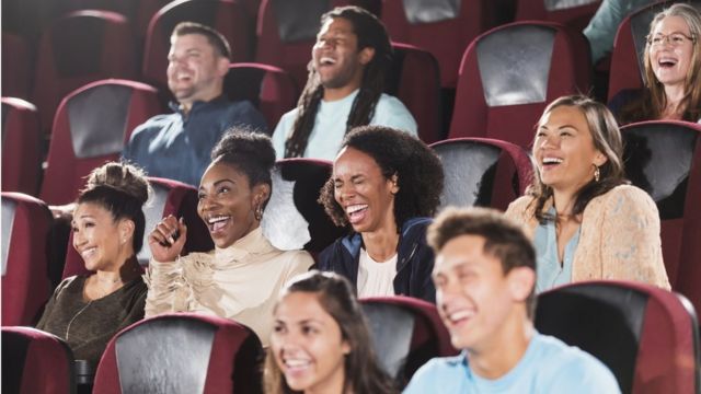 صورة لأشخاص يضحكون خلال جلوسهم على مقاعد مسرح