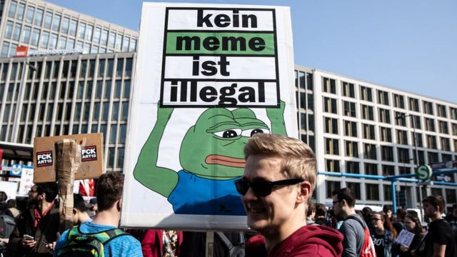A protestor holds a banner reading "No meme is illegal" during the "Save The Internet" demonstration in Berlin, Germany