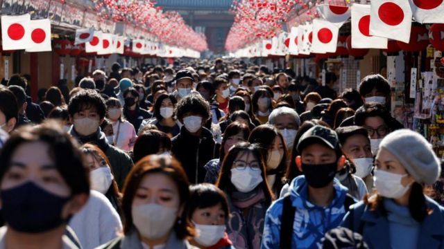 Visitantes usando máscaras protetoras caminham sob as decorações de Ano Novo na rua Nakamise, levando ao templo Senso-ji no distrito de Asakusa, um ponto turístico popular, em meio à pandemia de covid-19 em Tóquio, Japão