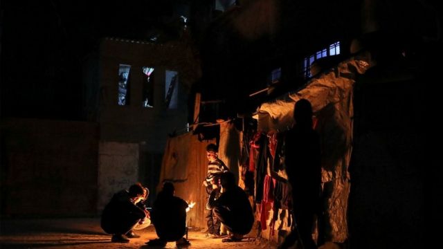 Boys warming themselves round a fire - power cuts are a regular occurrence in Gaza