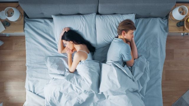 couple in bed, each facing one way