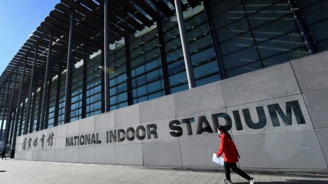 Una mujer camina por las afueras del National Indoor Stadium