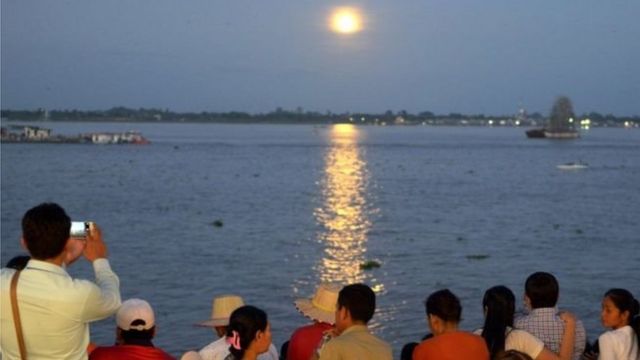 اجتمع العشرات لمتابعة القمر العملاق على ضفاف النهر المقابل للقصر الملكي في عاصمة كمبوديا بنوم بنه