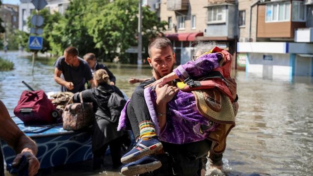 Police evacuate local residents from a flooded area after the Nova Kakhovka dam breached, amid Russia's attack on Ukraine, in Kherson on 7 June 2023