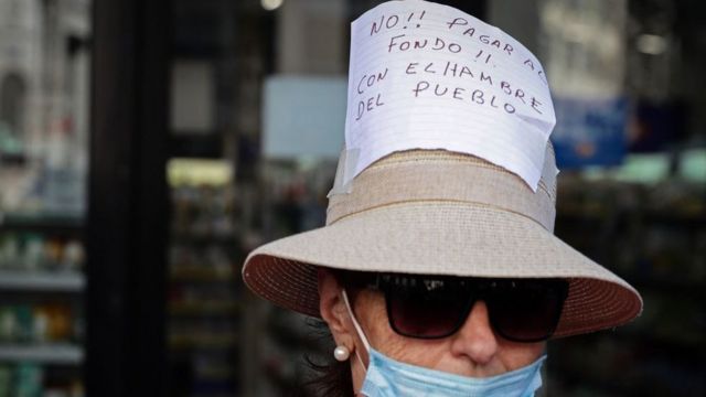 Una mujer con un cartel que dice: "No pagar al fondo con el hambre del pueblo"