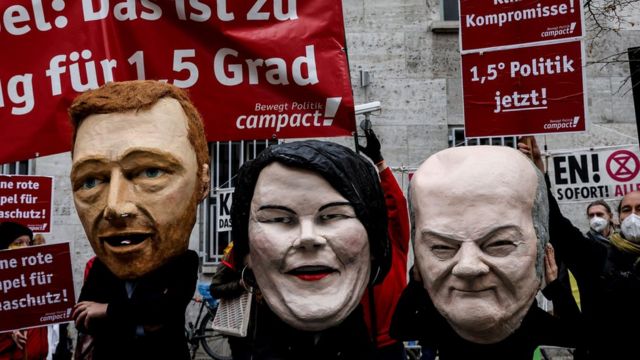 Маски лидеров трех партий новой коалиции Германии на демонстрации борцов за климат в Берлине, ноябрь 2021