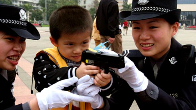 Члены женского полицейского патруля в китайском городе Наньнине дали мальчику подержать пистолет