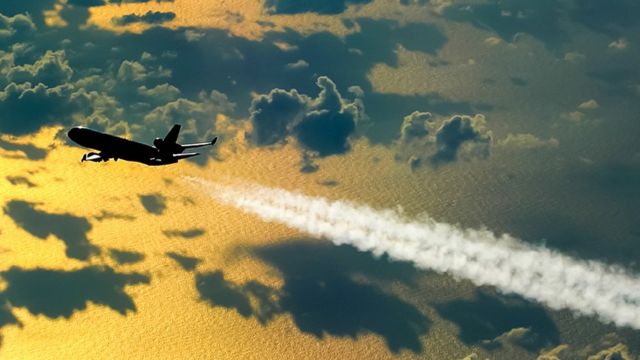 Avión de pasajeros en vuelo dejando una estela de humo