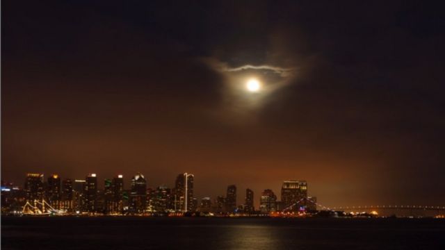 A superlua surge em nuvens acima da cidade de San Diego, Califórnia, EUA
