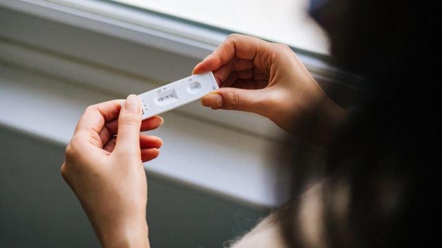 Mulher olhando resultado de teste rápido de covid-19