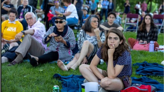 Residents of the US capital Washington DC watch the Congressional Hearing on a big screen in a city park