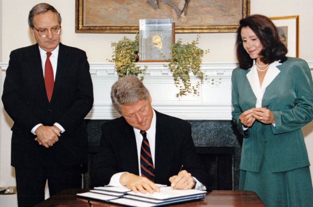 Nancy Pelosi osserva Bill Clinton firmare un ordine esecutivo.