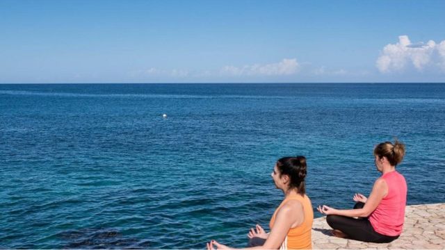 Mulheres meditam em frente ao mar