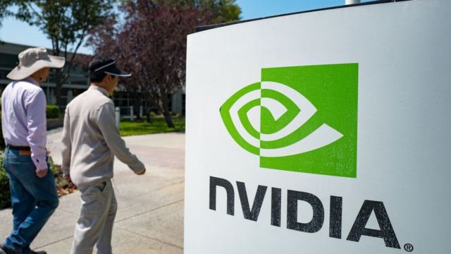 Two people walk in front of the Nvidia logo in Silicon Valley