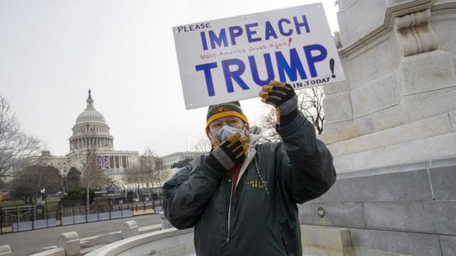 Homem com placa que pede impeachment de Trump