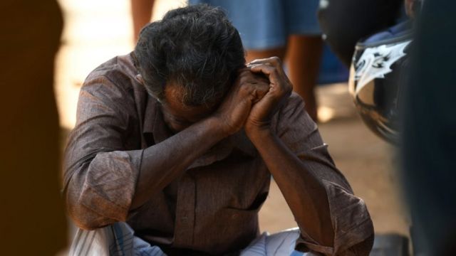 A man is hunched over outside a hospital in Batticaloa