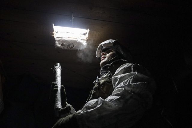 Militar olha para cima, para fresta no teto por onde passa luz