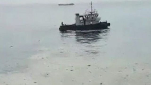 Boat in water surrounded by oil