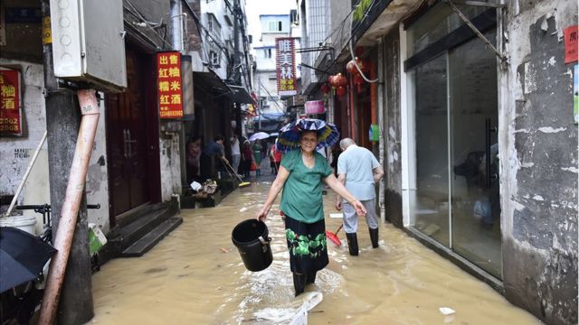 福建建瓯，一名妇女行过被洪水淹没的街道