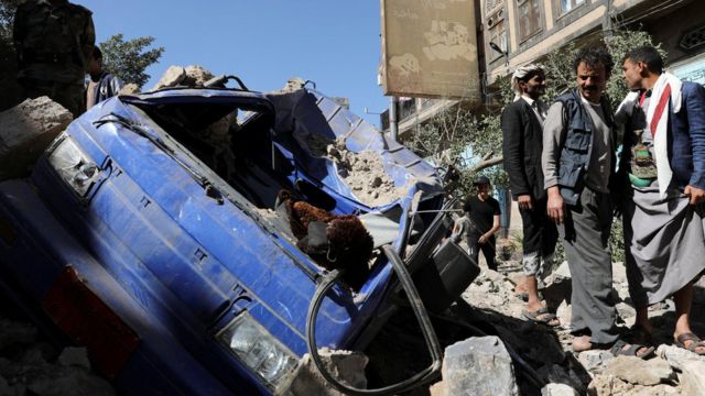ضابط وأفراد يقفون بجانب مركبة دمرتها غارة جوية بقيادة السعودية في صنعاء في 24 ديسمبر/كانون الأول 2021