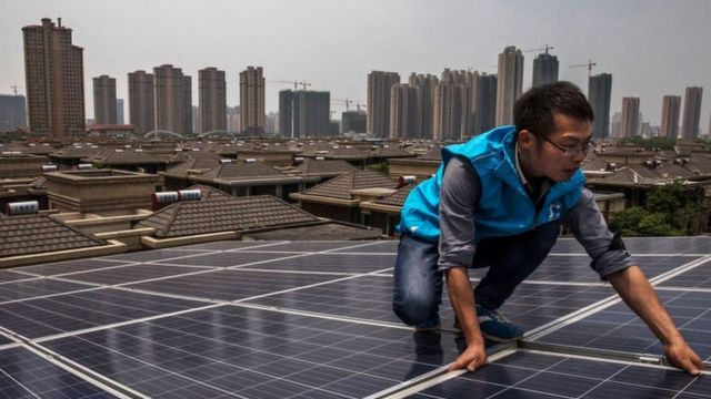 Hombre colocando paneles solares en China.
