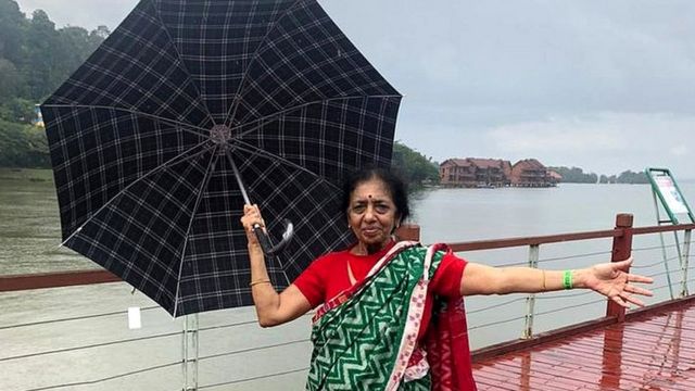 Nalini debout avec un parapluie devant une grande étendue d'eau