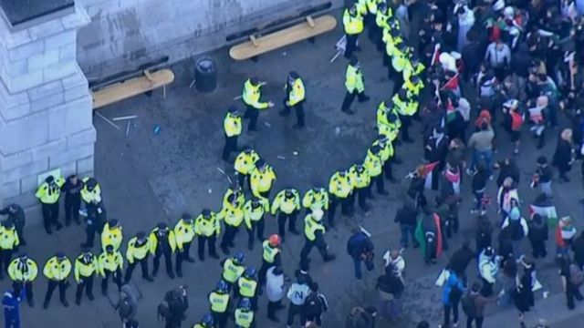 Police in Trafalgar Square form a semi-circle around a detained man