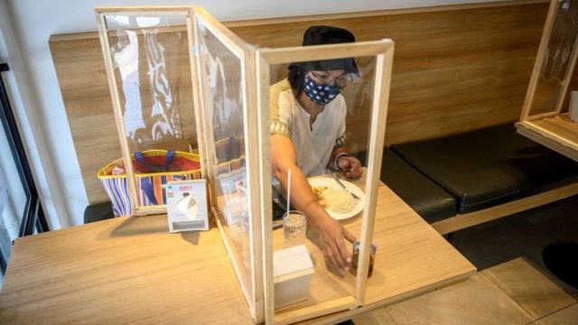 Customer eats by protective screen at a restaurant in Bangkok