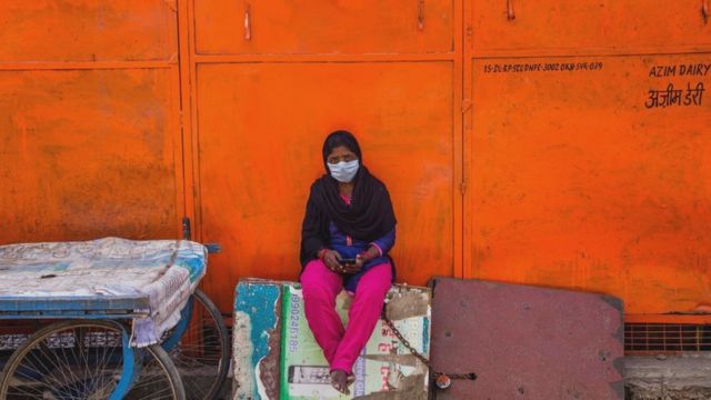 Una mujer india con una mascarilla en una calle desierta.