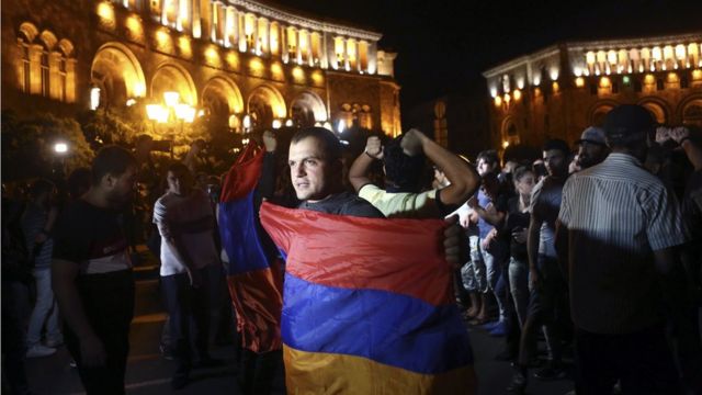 Мужчина на митинге в Ереване держит армянский флаг