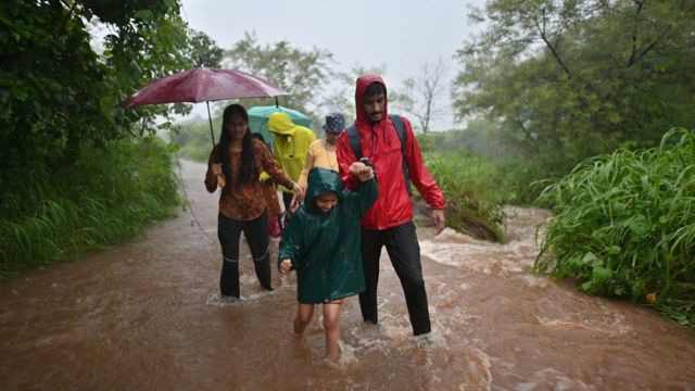 Uma família caminha por uma área completamente inundada