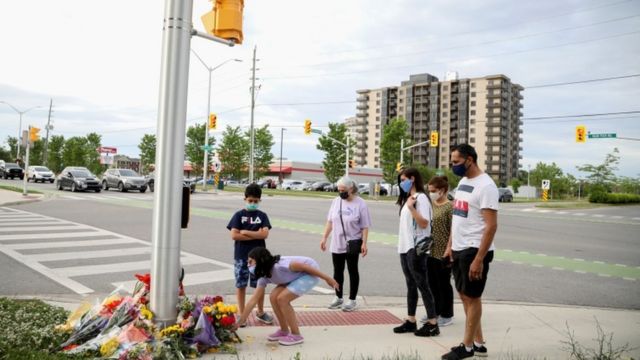 Personas se acercan a dejar flores a un homenaje en plena calle en Ontario, Canadá.