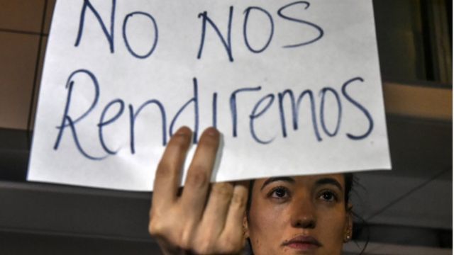 Una joven sostiene un cartel: "No nos rendiremos"