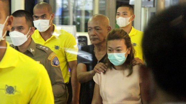 Sararat Rangsiwuthaporn, accused of killing 14 people using cyanide, is escorted by authorities after her arrest.