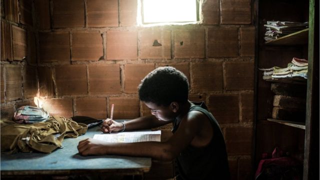 Foto ilustrativa mostra criança estudando em ambiente precário