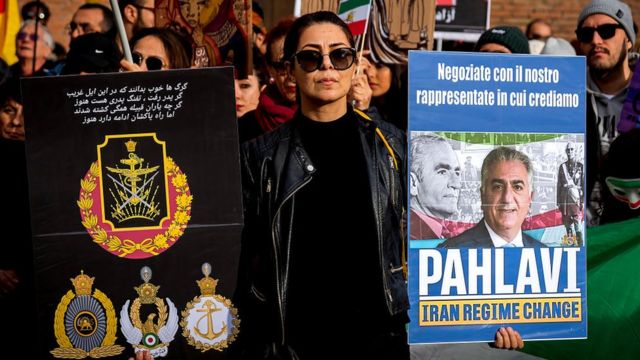 معترضی در در تظاهرات حمایت از جنبش «زن، زندگی، آزادی» رُم ایتالیا پلاکاردی شاهزاده رضا پهلوی را در دست گرفته است